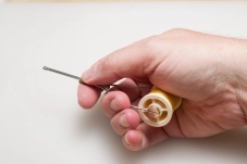 The no-name ceramic bobbin holder in the hand The no-name ceramic bobbin holder in the hand